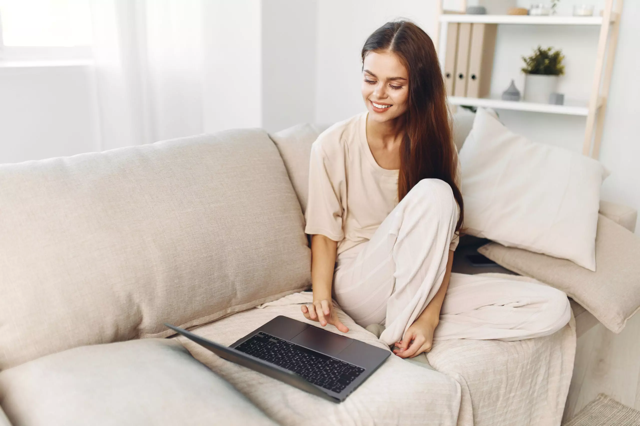 Smiling Woman Working on Laptop in Cozy Living Room - Natucci Estetica natucci estetica